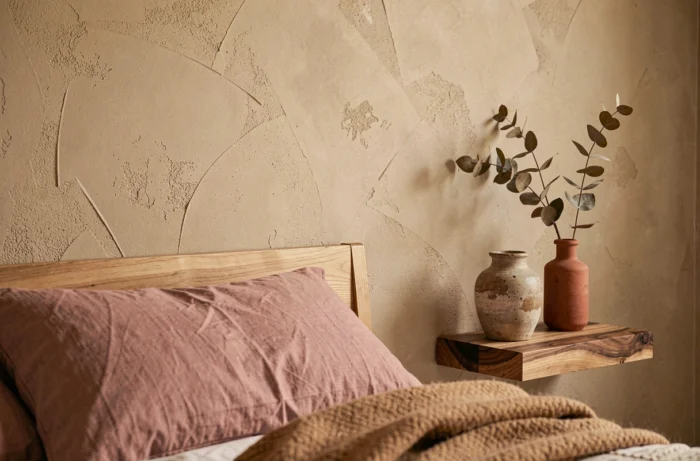 Détail mural chambre peinte en beige sable chaud avec décoration textile en lin et laine et accessoires en céramique terracotta